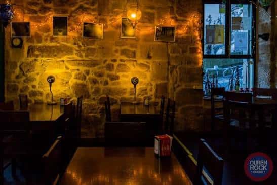 Sala acogedora con paredes de piedra y mesas iluminadas
