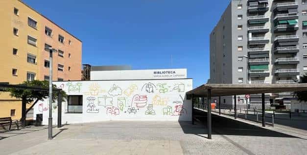 Fachada frontal de la biblioteca con mural colorido y señalización clara del nombre