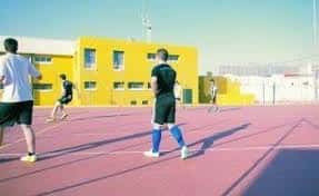 Jugadores entrenando en cancha deportiva exterior amarilla del complejo Quinta de la Paz