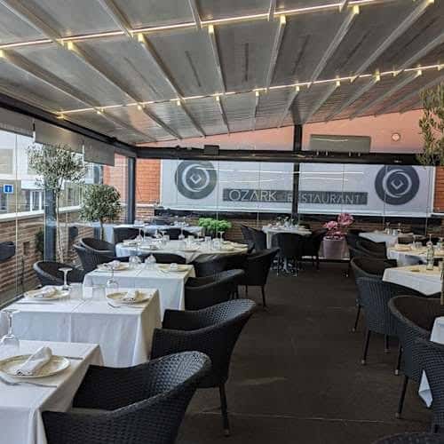 Interior del restaurante Ozark con mesas dispuestas para cena y decoración moderna