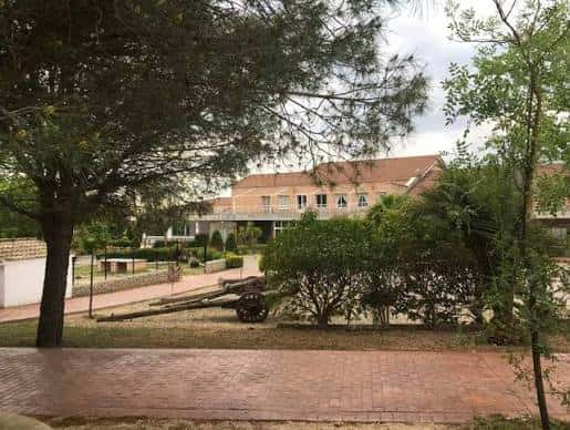 Vista exterior del Club Polideportivo El Encinar con jardines y cañón decorativo