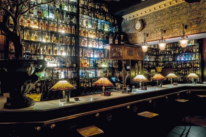 Interior del bar La Posada con estanterías de botellas y lámparas estilo Tiffany