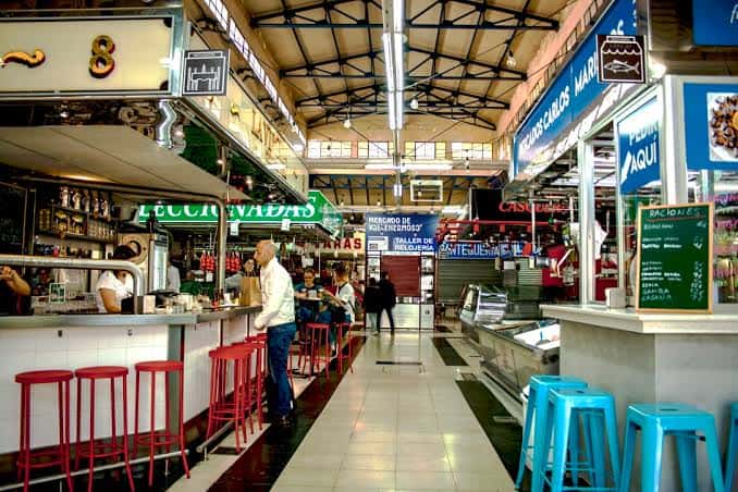 Interior del mercado mostrando pasillos con puestos de comida y barra de tapas