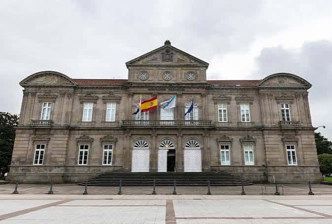 Entrada monumental de la sede con banderas española, gallega y europea