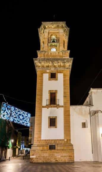 Torre de la iglesia iluminada por la noche con decoración festiva cercana
