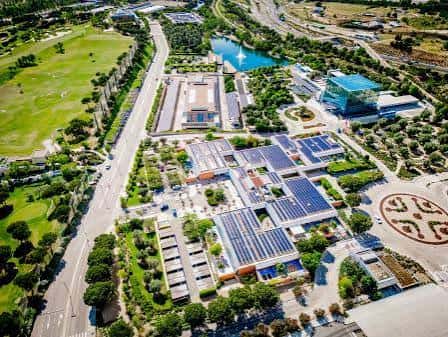 Vista aérea panorámica del complejo con edificios modernos, zonas verdes y piscinas decorativas