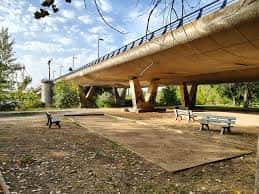 Vista del Puente de los Tres Árboles con bancos y zona ajardinada
