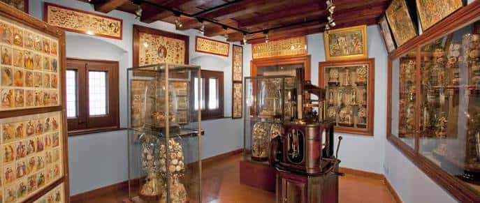 Sala de exposiciones con vitrinas de vidrio y arte religioso enmarcado
