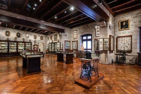 Gran sala principal con techos de vigas de madera y exhibición de máquinas de coser antiguas