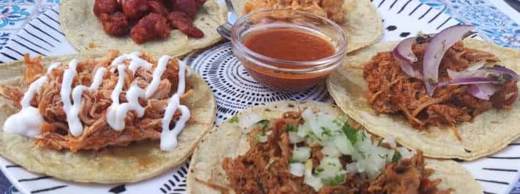 Plato de tacos mexicanos servidos en tortillas con salsas y guarniciones
