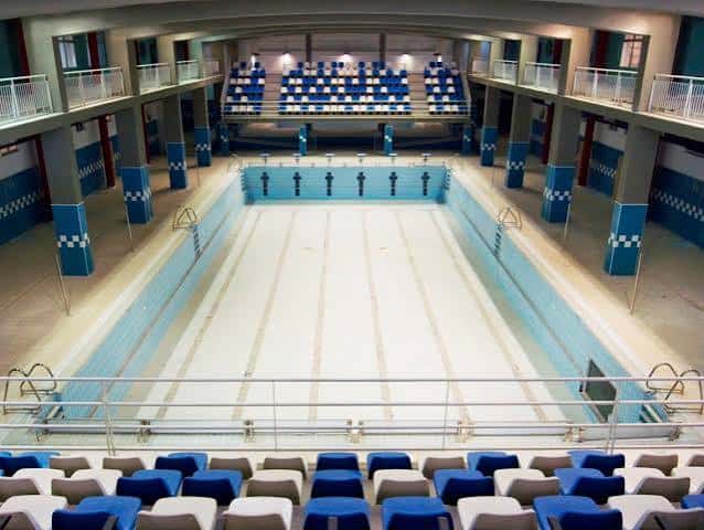 Piscina olímpica cubierta con gradas azules y blancas en el Complejo Guillermo Molina