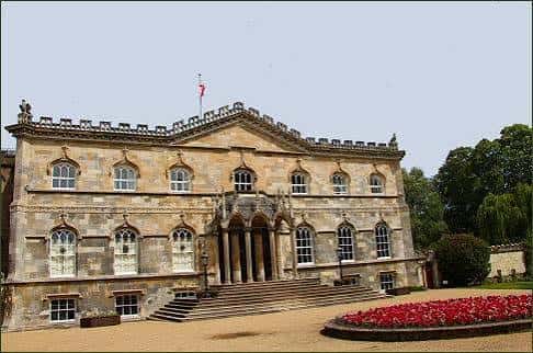 Fachada principal del palacio con jardín de flores rojas