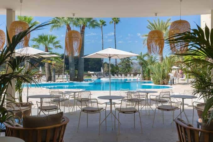 Terraza de restaurante junto a la piscina con decoración tropical y vistas al mar