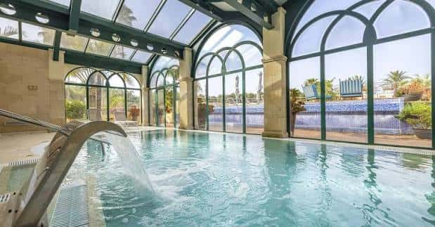 Piscina interior climatizada con arquitectura de arcos y acceso directo al jardín