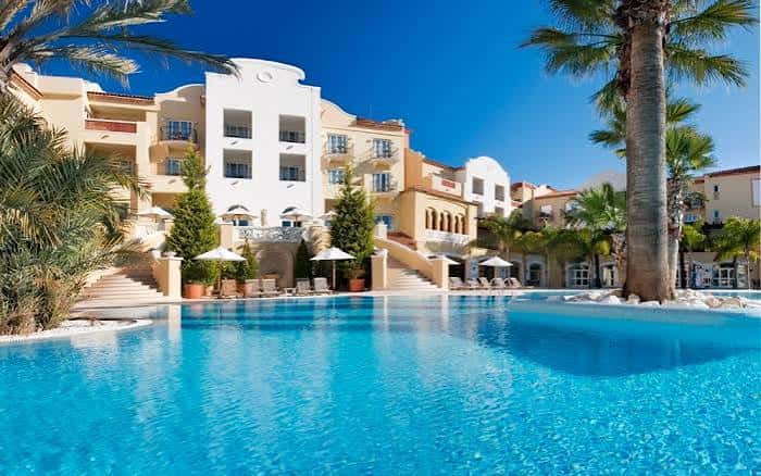 Fachada principal del hotel con piscina infinita y jardines mediterráneos