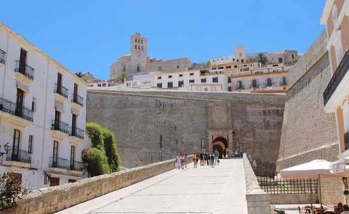 Vista diurna del Portal de Ses Taules con turistas cruzando el puente y la muralla renacentista al fondo