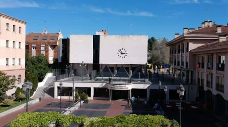 Vista exterior del edificio de la biblioteca en Pozuelo de Alarcón, con reloj en la fachada y escalinata de acceso