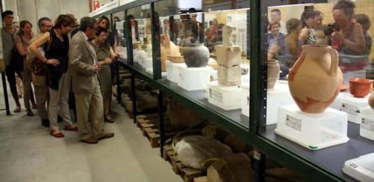 Grupo de visitantes observando cerámicas y objetos expuestos en las vitrinas del museo
