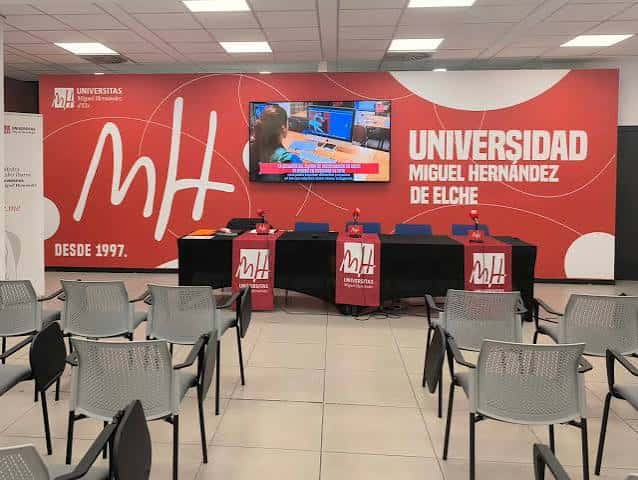 Aula Plaça de Baix preparada para un evento con mesa de ponentes y sillas dispuestas