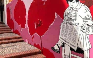 Escalera exterior decorada con murales artísticos en tonos rojos