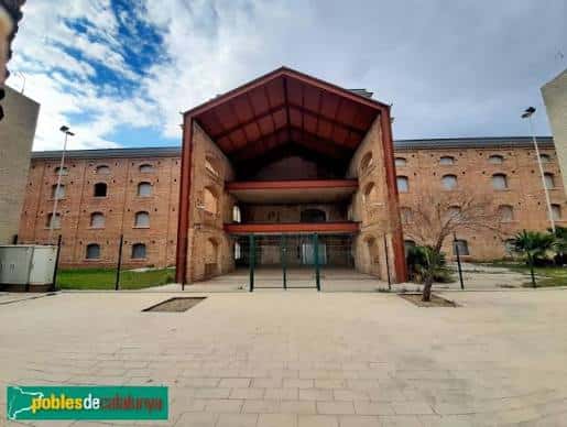 Vista frontal de la Fàbrica CACI mostrando su arquitectura industrial con fachada de ladrillo y estructura metálica roja