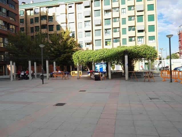 Área cubierta con pérgola verde en la plaza, ideal para eventos al aire libre