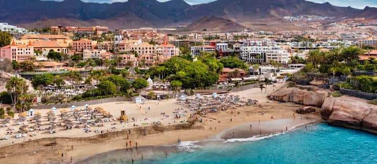 Vista panorámica de Playa del Duque con edificios costeros y montañas al fondo
