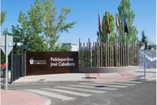 Entrada principal del Polideportivo Municipal José Caballero con letrero y banderas