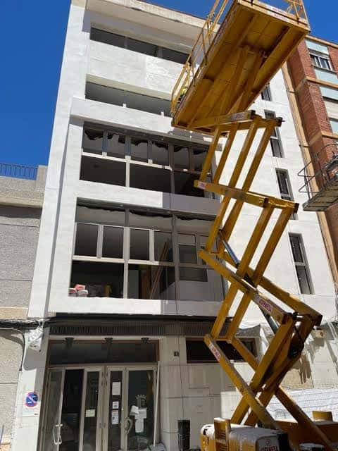 Fachada principal del edificio en proceso de renovación con plataforma elevadora