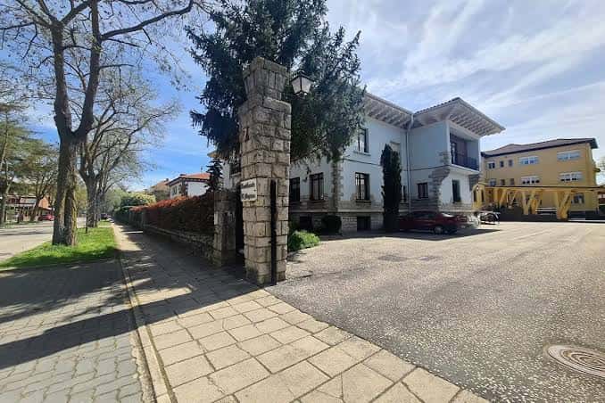 Entrada principal de una residencia tradicional con portón de piedra y entorno arbolado