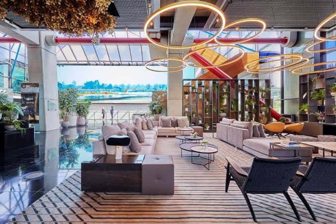Lobby moderno del hotel con sofás cómodos, iluminación circular decorativa y vistas al río