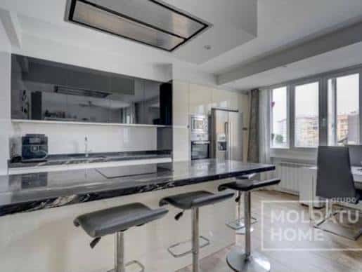 Cocina contemporánea con isla central y barra de desayuno en los apartamentos