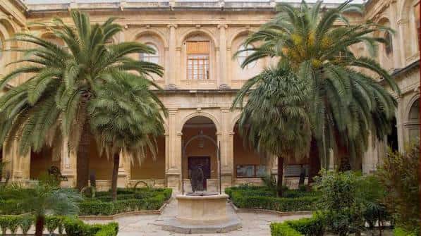 Patio interior del colegio con palmeras, fuente y arquitectura clásica