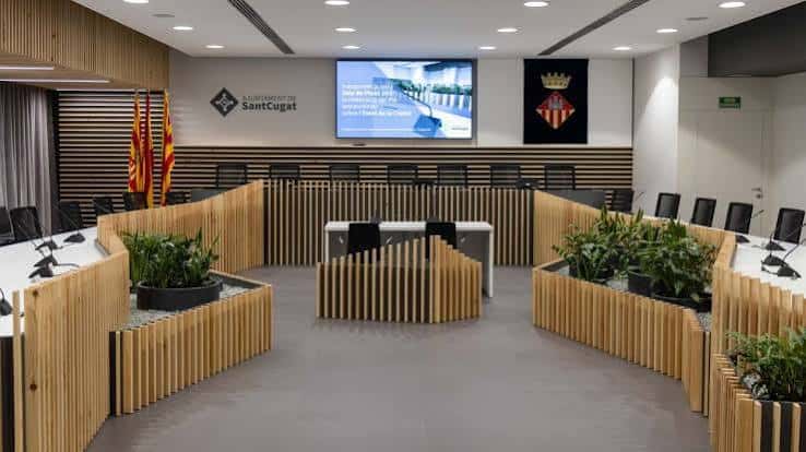 Sala de plenos moderna con mobiliario de madera y pantallas digitales