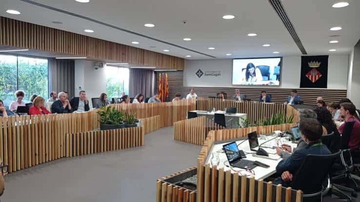 Reunión en curso en la sala de plenos con participantes sentados