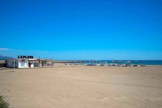 Playa amplia con chiringuito 'La Playa' y hamacas frente al mar