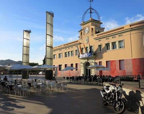 Vista diurna de la Plaça de la Vila con mesas y sombrillas dispuestas para eventos al aire frente al ayuntamiento