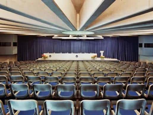 Interior del auditorio con filas de asientos y escenario preparado para eventos