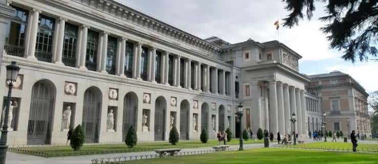 Fachada del Museo del Prado con columnas y estatuas en el jardín