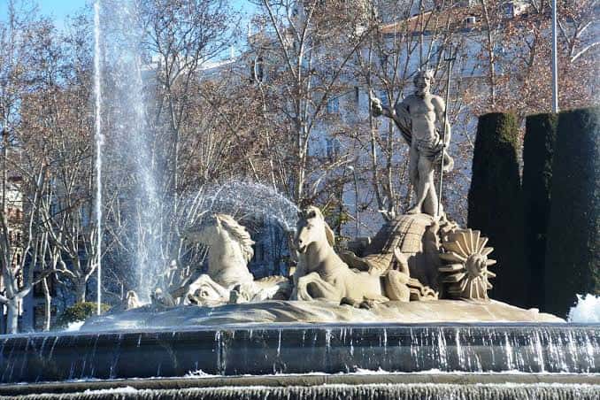 Fuente de Neptuno con escultura ecuestre y chorros de agua bajo cielo despejado