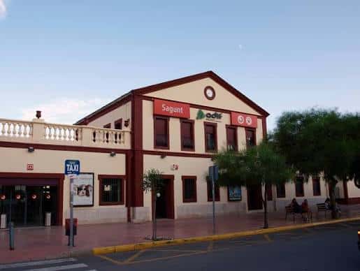 Fachada principal de la Estación de Sagunto con el letrero 'Sagunt' y señalización de ADIF
