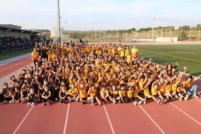 Gran grupo de atletas y entrenadores posando en la pista de atletismo del club