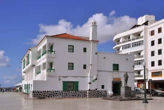 Vista exterior del edificio de la UNED en Arrecife con fachada blanca y detalles en piedra volcánica