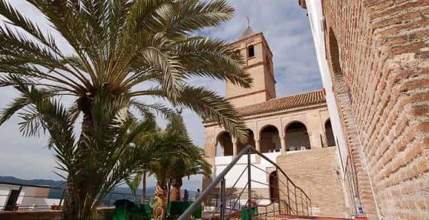 Fachada exterior del edificio histórico con palmeras y torre