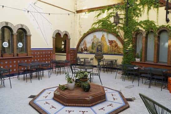 Vista del patio con murales decorativos y vegetación enmarcando el espacio