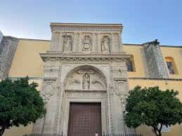 Vista exterior frontal de la basílica con árboles ornamentales a los lados