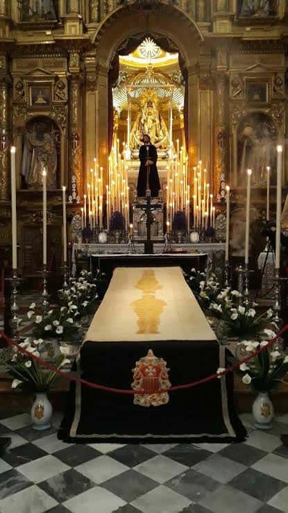 Interior del altar mayor de la basílica con decoración litúrgica y velas encendidas