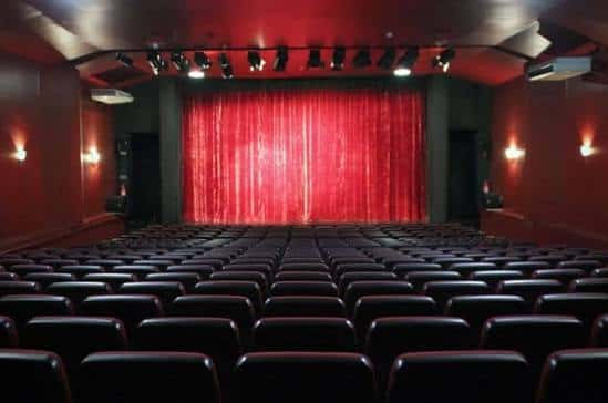 Interior del auditorio con butacas rojas y cortina de escenario