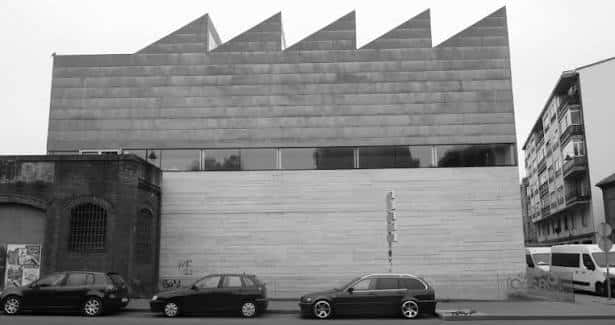 Fachada lateral del centro cívico con diseño angular y estacionamiento frente a él