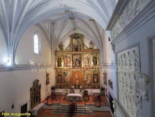 Interior del monasterio mostrando el retablo mayor dorado y bóvedas góticas